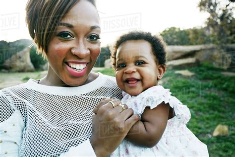 Black mother holding baby daughter in field - Stock Photo - Dissolve