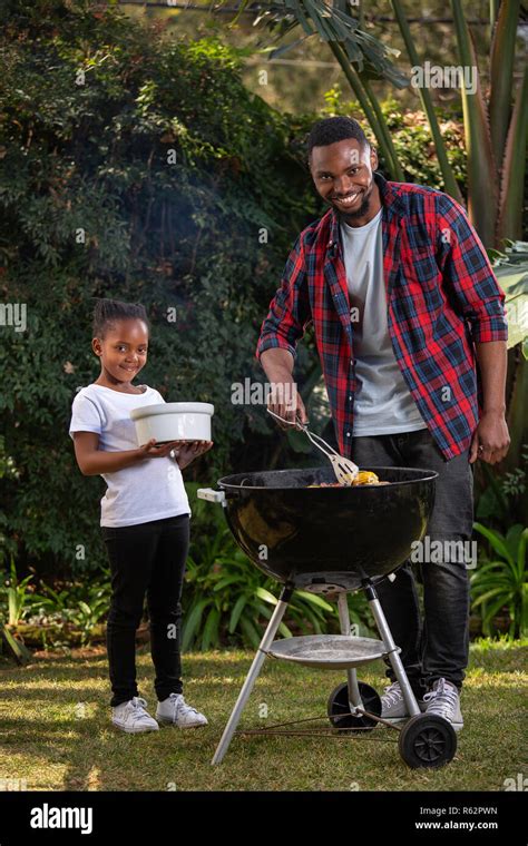 A girl helping her dad at a barbecue Stock Photo - Alamy