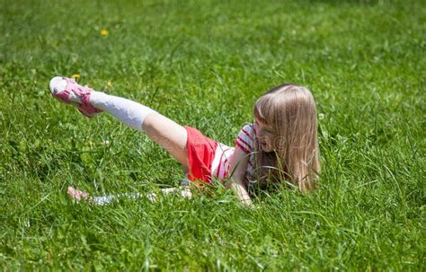 Little girl lying on grass stock image. Image of merriment - 68324177