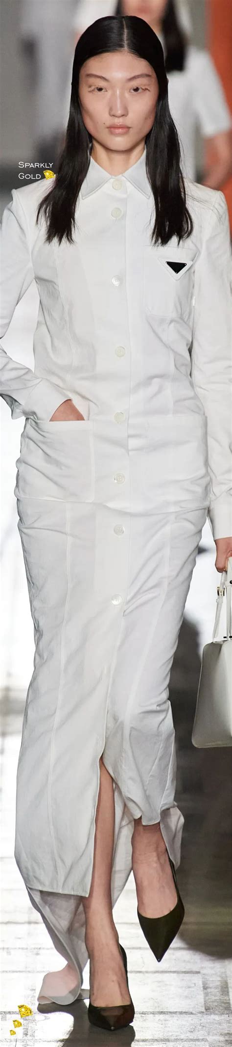 a woman walking down a runway wearing a white dress