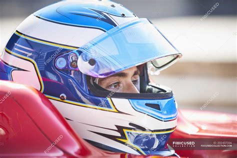 Close up formula one race car driver in helmet looking away ...