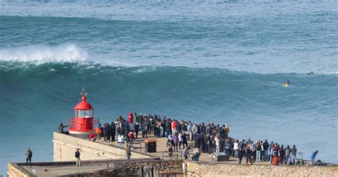 People watching the big giant waves crashing near the Fort of Nazare ...