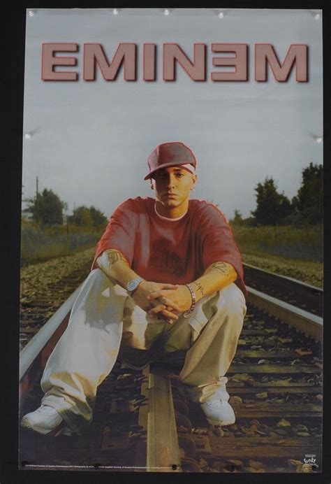 a man sitting on train tracks in front of the words eminiem above him