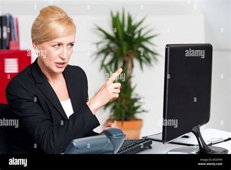 Angry woman in office indicating at computer led screen Stock Photo - Alamy