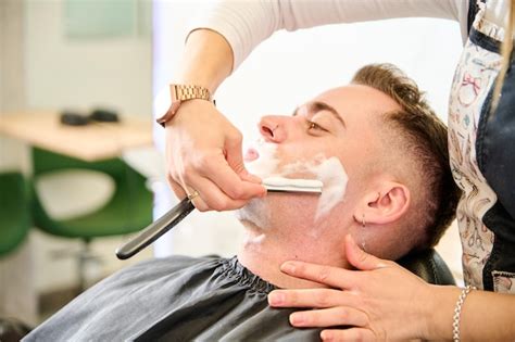 Premium Photo | Young man shaving with straight edge razor by ...