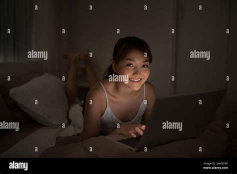 Bedroom evening - woman with laptop lying down in bed Stock Photo - Alamy