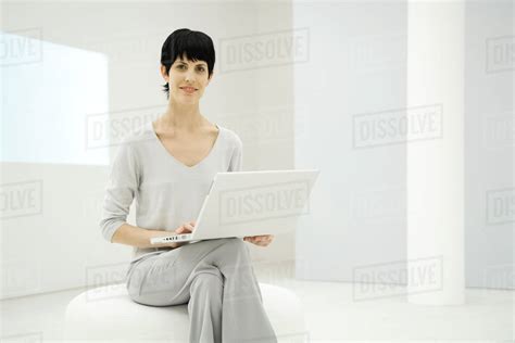 Woman sitting, holding laptop computer, smiling at camera - Stock Photo ...