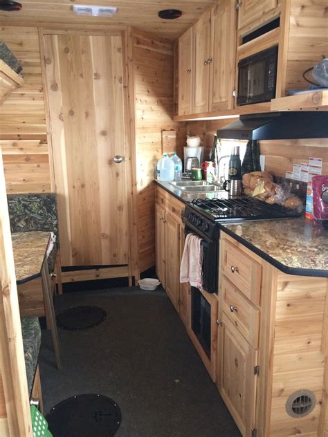 a small kitchen with wood paneling and black counter tops, along with ...