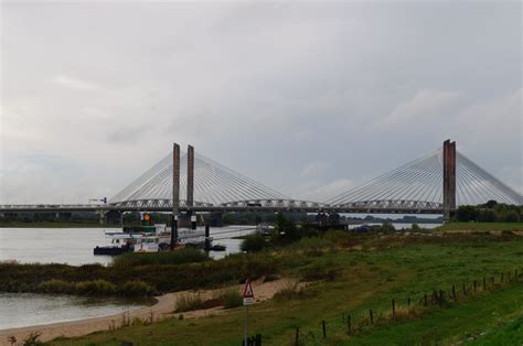 a large bridge spanning over a body of water next to a lush green field ...