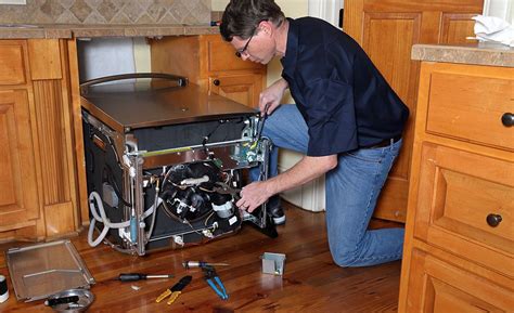 A person using a hole saw for installing dishwasher supply lines ...