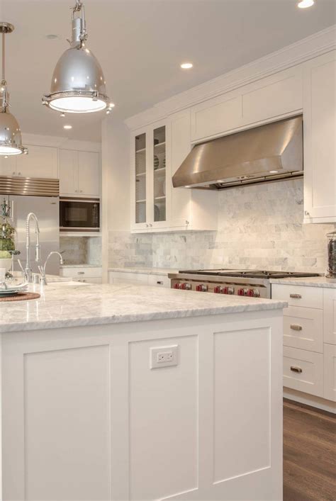 White kitchen with marble counter tops and pendant lights