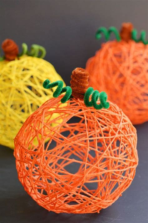 three orange and yellow yarn pumpkins sitting on top of a black surface ...