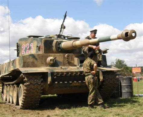 two men standing next to an army tank