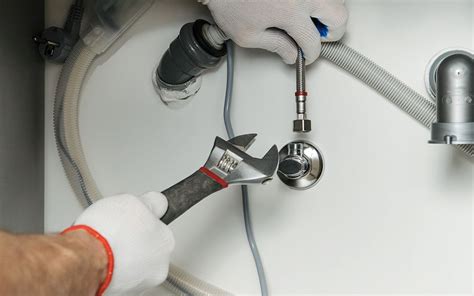 A person tapping the water supply to install a refrigerator water line ...