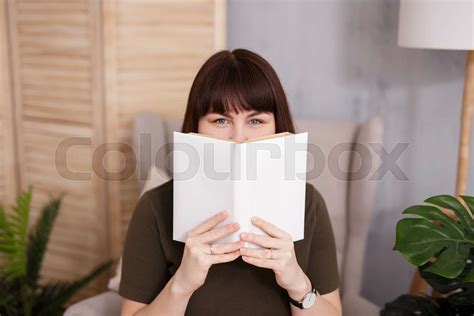 Woman covering her face with white book | Stock image | Colourbox