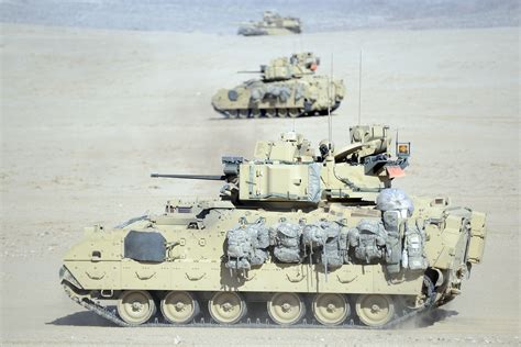 A M1-A1 Abrams tank and M2 Bradley fighting vehicles conduct a bounding ...