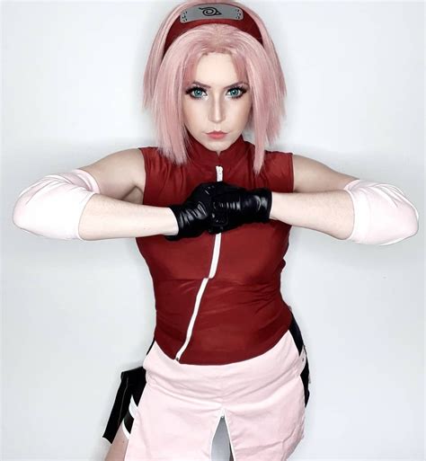 a woman with pink hair and black gloves posing for a photo in front of ...