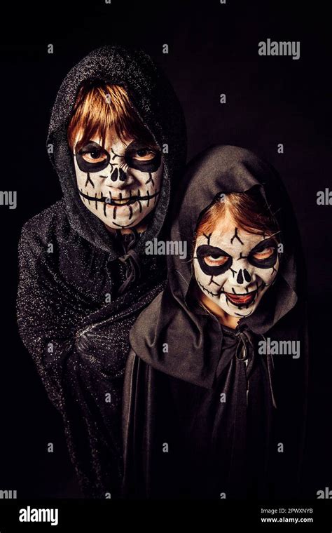 Two kids wearing dark robes and scary face paint at Halloween Stock ...