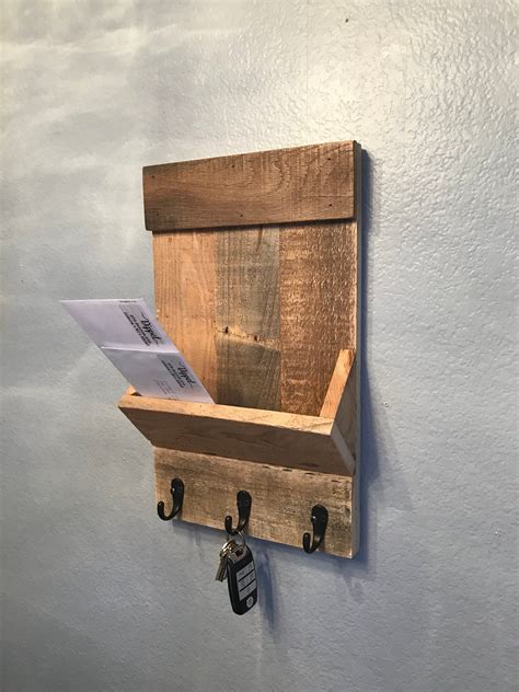 a wooden shelf mounted to the side of a wall with hooks and papers on it