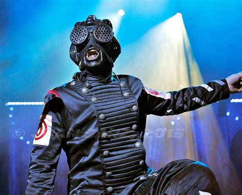 a man in a black outfit and gas mask on stage