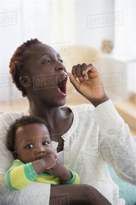 Yawning Black mother holding baby boy - Stock Photo - Dissolve