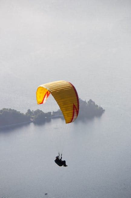 Faceless person flying paraglider over green countryside · Free Stock Photo