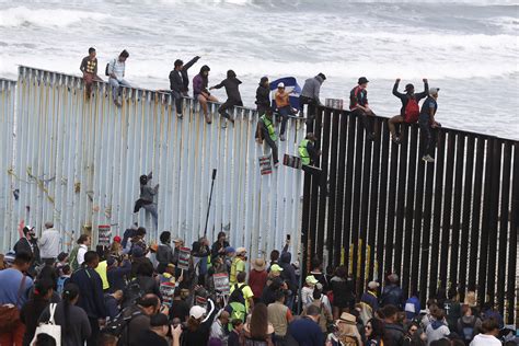 Migrants from 'caravan' scale border wall in protest after denied entry ...