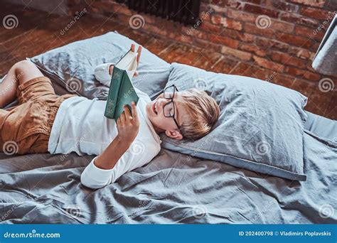 Cheerful Preschool Boy Reading a Book and Lying Down on a Bed Stock ...