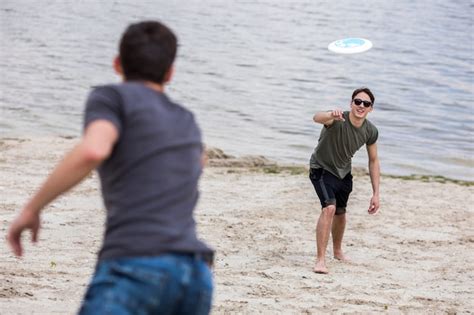 Free Photo | Adult man throwing frisbee for friend on beach