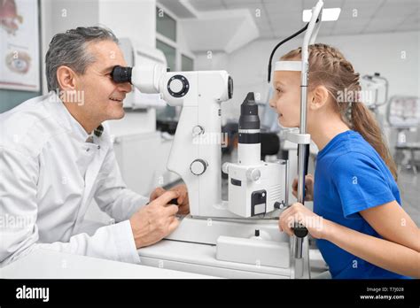 Professional doctor ophthalmologist examining eyes of pretty patient ...