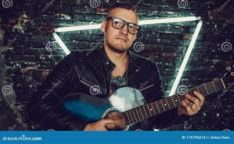 Tattooed Man Playing Guitar Near Illuminated Wall. Stylish Guy with ...