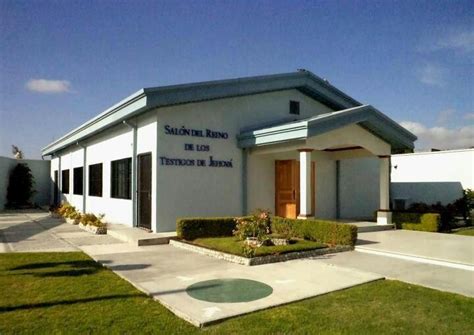 the front of a building with grass and bushes