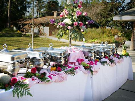 an outdoor buffet table with flowers and silverware on it's tablescloths