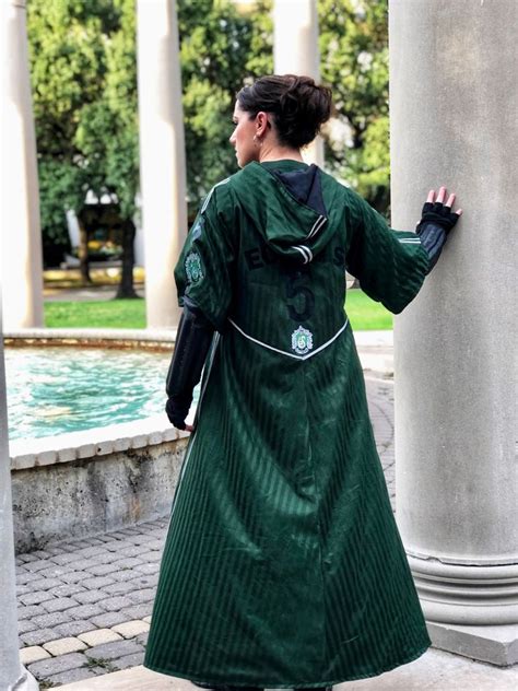 a woman in green coat standing next to columns