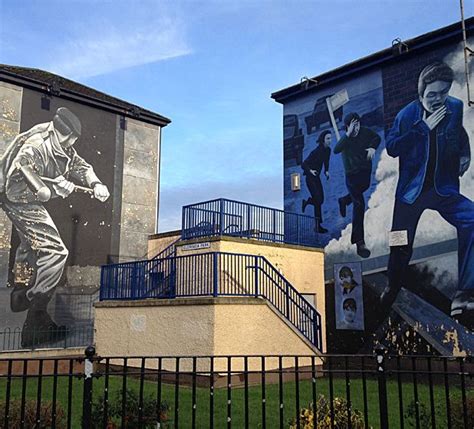 two large murals are painted on the side of buildings in front of a ...