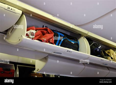 Open filled overhead luggage compartment on an airplane during boarding ...