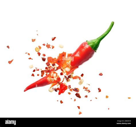 Chili flakes bursting out from red chili pepper over white background ...