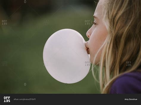 Little girl blowing a bubble with chewing gum stock photo - OFFSET