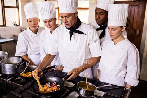 Head chef teaching his team to prepare a food in kitchen — 20s, 40 44 ...