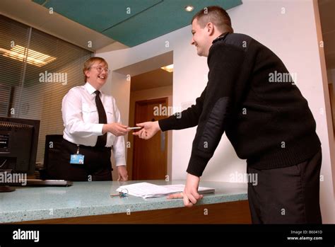 A SECURITY GUARD ON PATROL SIGNS IN AT A FRONT DESK WITH ANOTHER Stock ...