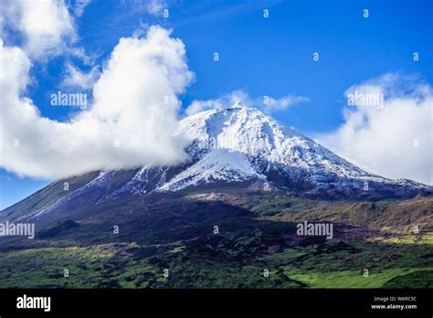 Mount Pico volcano summit covered in snow under blue sky and clouds, in ...