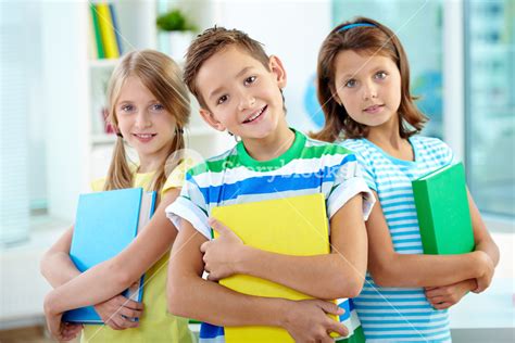 Portrait Of Happy Classmates With Books Looking At Camera In Classroom ...