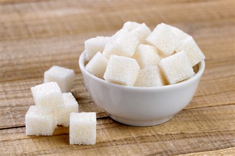 Sugar cubes in bowl on wooden table