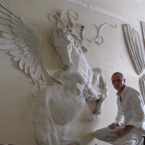 a man standing next to a white horse sculpture on the side of a wall in ...