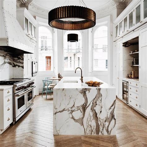 a large kitchen with marble counter tops and white cabinets, along with ...