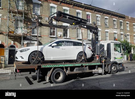 car being towed away on a flat bed truck by local council enforcement ...