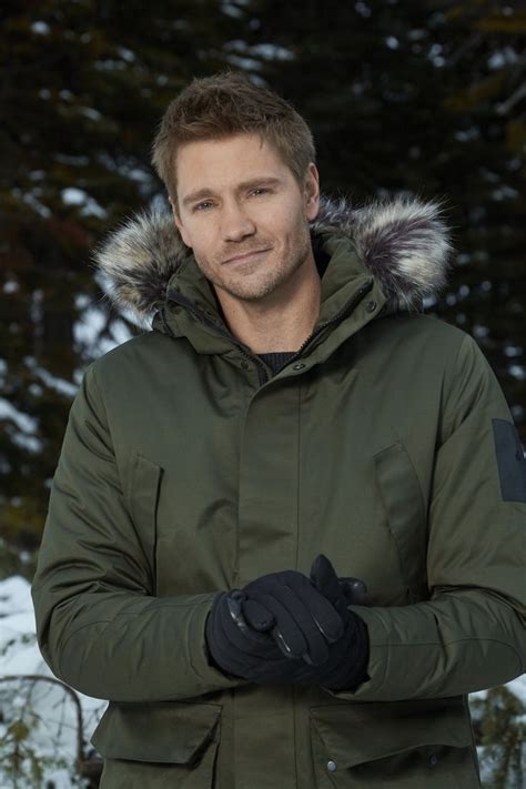 a man standing in the snow wearing a green jacket and black gloves with ...