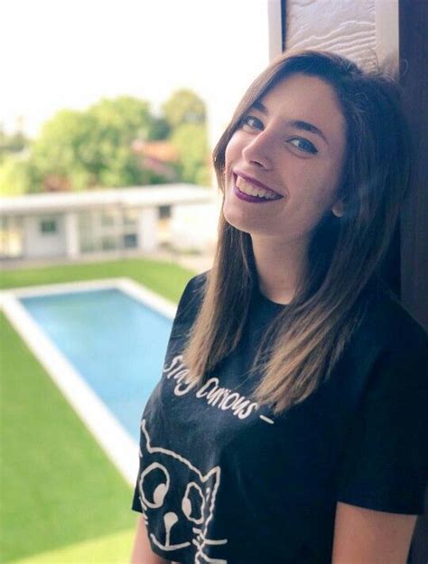 a woman standing in front of a pool wearing a t - shirt with a cat on it