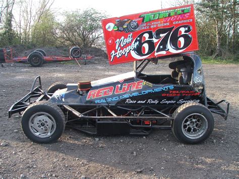 a race car is parked in the dirt with a sign on it's side