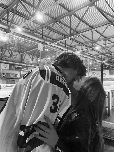 a man and woman kissing each other in front of a hockey goalie's jersey